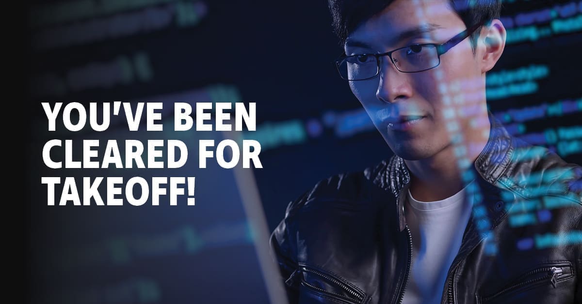 A man working at a computer with an overlay image of code on a scree with the text, 'You've been cleared for takeoff!'